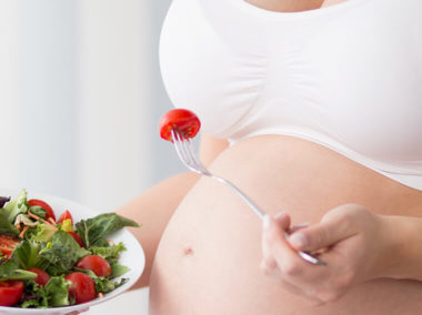 Kobieta w ciąży je sałatkę.