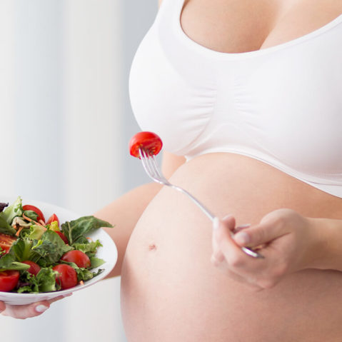 Kobieta w ciąży je sałatkę.