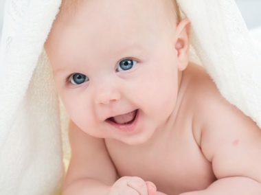 Uśmiechnięty niemowlak pod kocem